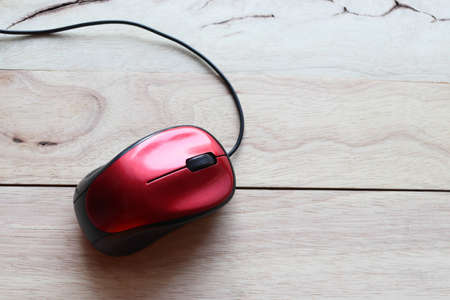 Red computer mouse on wooden table. Top view with copy space.の写真素材
