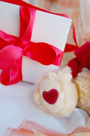 Gift box with red ribbon and teddy bear footの写真素材