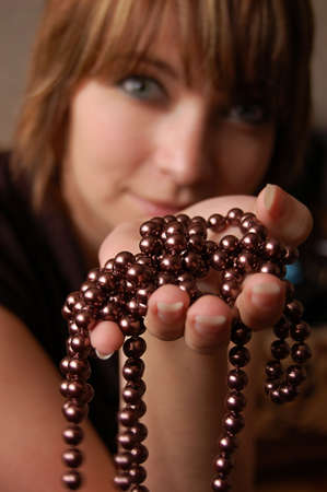 Girl holding brown pearl necklace, focus on handの写真素材