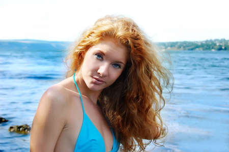 portrait of beatiful redhead girl over blue watersの写真素材