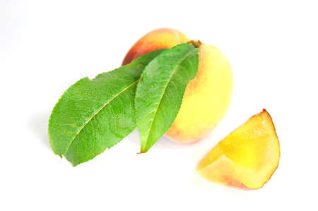 ripe peach fruit with green leafs isolated on whiteの写真素材