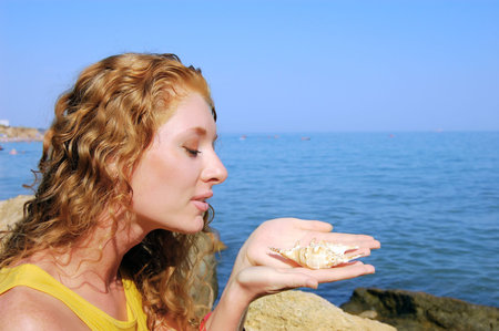 beautiful girl holds a seashell in hands, seashore