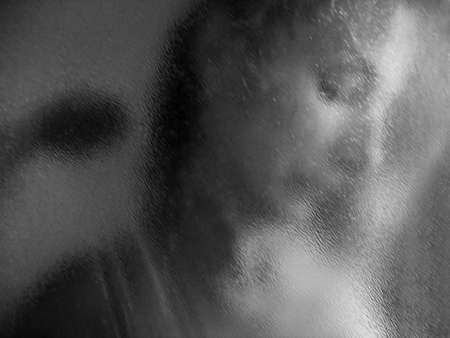 beautiful woman face silhouette behind condensated shower glassの写真素材