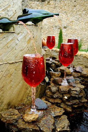 fountain of red wine pouring from bottlesの写真素材