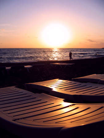 chaise longues ashore over sunset skyの写真素材