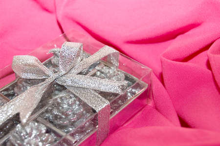 silver gift box over pink fabricの写真素材