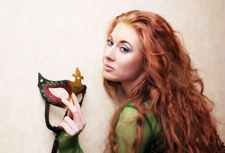 beautiful red-head woman holding maskの写真素材
