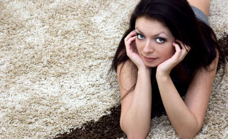 Beautiful brunette lying on carpetの写真素材