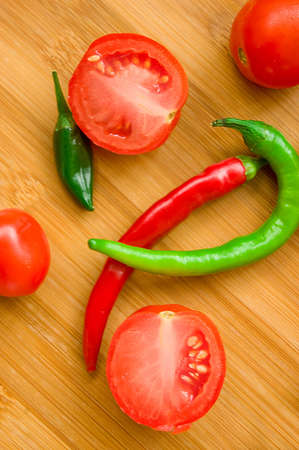 Some tomatos, green and red pepper on wooden backgroundの写真素材