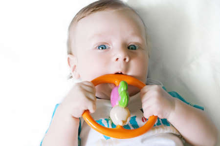 Little baby boy playing with rattle over light backgroundの写真素材