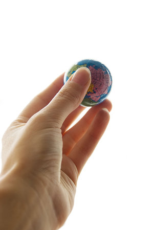 Small globe in human hand isolated over whiteの写真素材