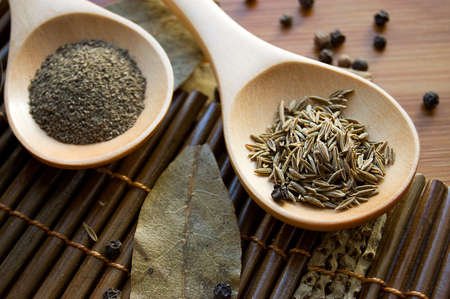 Pepper, zira and bay leaf on wooden plateの写真素材