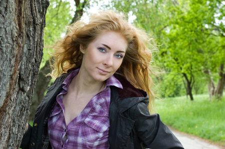 Redheaded woman with wind in hair under tree