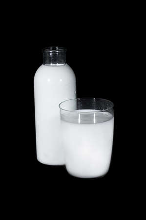 Bottle and glass of milk over blackの写真素材