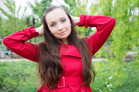 Brunette woman with long hair and red trench outdoorの写真素材