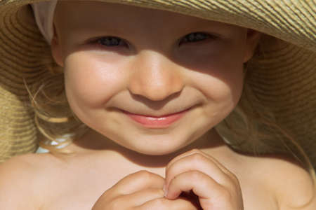 Adorable baby girl face sunlit under hatの写真素材