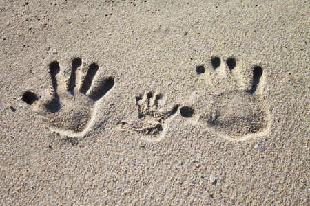 Three palm imprints of family on sandの写真素材