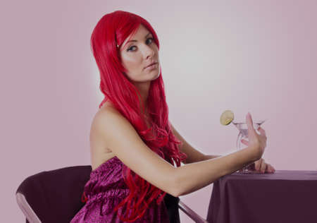 Red-haired sad woman with cocktail sitting at tableの写真素材