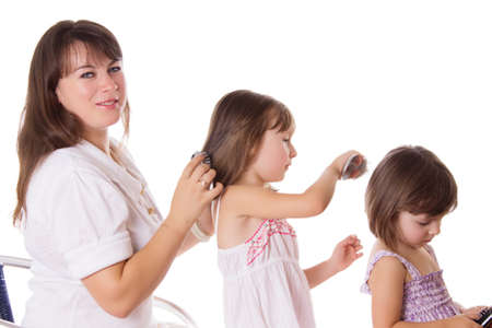 Mother and two daughters combing hair to each othre isolated on whiteの写真素材