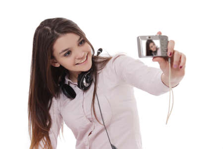 Cheerful schoolgirl taking her own pictures over whiteの写真素材