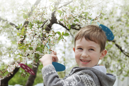 Happy boy among blooming garden