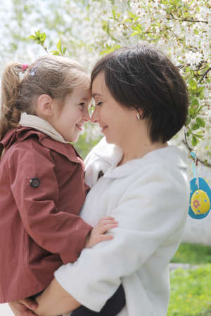 Happy mother and baby girl hugging among spring gardenの写真素材