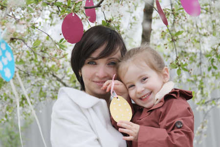 Happy mother and daughter in blooming garden decorating for Easterの写真素材