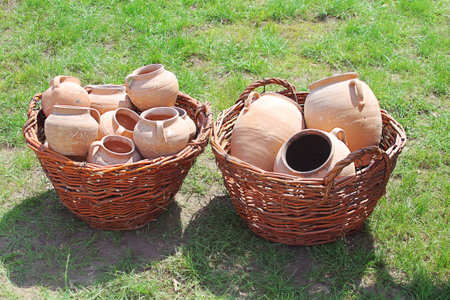 Ancient clay pots in basket over green grass