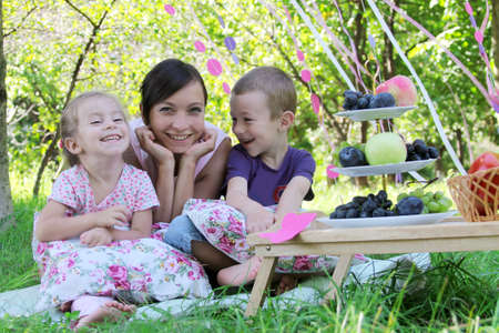 Happy mother and two children laughing on summer picnicの写真素材