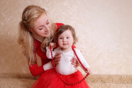 Lovely mother with one year baby girl and red beadsの写真素材