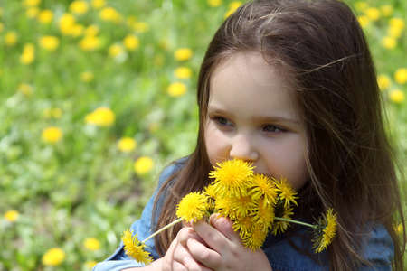 Beautiful girl with long hair smelling dandelion in springの写真素材