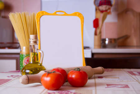 Tomatoes, spaghetti and  menmu board on table in the kitchenの写真素材