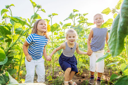 Happy children jumping, having fun in the field of sunflowersの写真素材