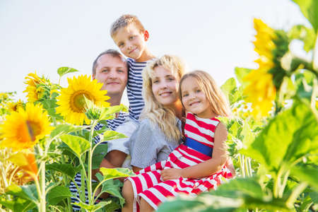 Happy family with two children in sunflower fieldの写真素材