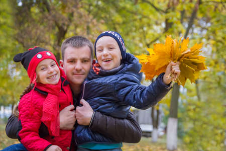 Happy father with two children in autumn parkの写真素材