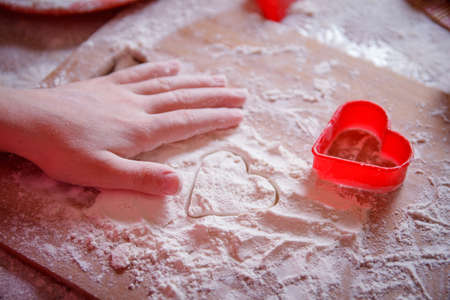 Girl hand on wooden board making heart shape on flourの写真素材