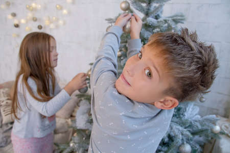 Boy and girl decorating Christmas tree with ballsの写真素材