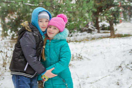 Sister and brother among snowy forest huggingの写真素材