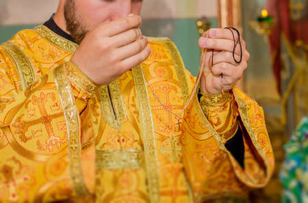 Priest hands holding golden chain with cross during christeningの写真素材