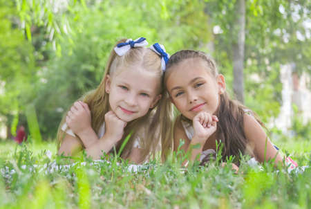 Two smiling girls lying on green  grass in the park in summerの写真素材