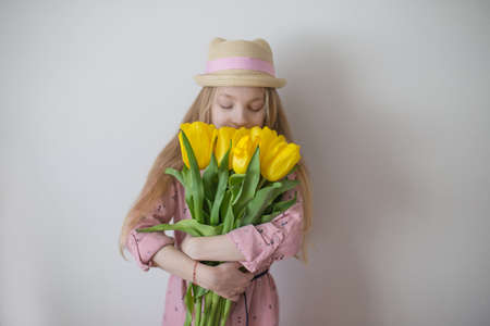 Pretty teen girl smelling yellow tulips, focus on flowersの写真素材