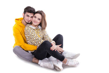 Young couple in yellow hugging and sittin in white studioの写真素材