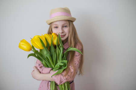 Pretty teen girl in pink dress with big bouquet of yellow tulipsの写真素材