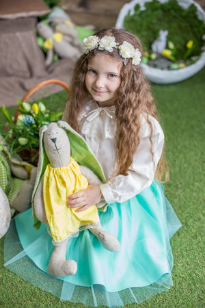 Cute little child girl with toy bunny among Easter studio decorationの写真素材