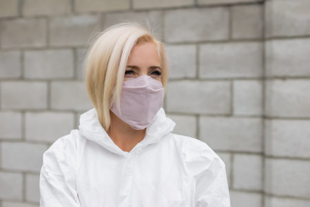 Woman in black mask and white protective suit outdoorsの写真素材