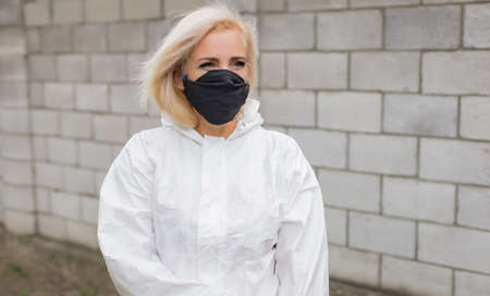 Woman in black mask, white protective suit and glovesの写真素材