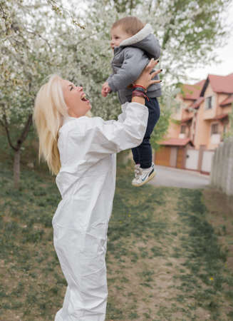 Happy woman in white protective suit meeting baby boyの写真素材