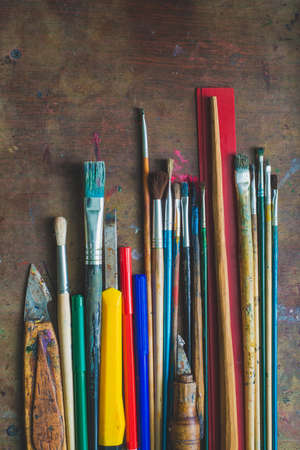 Set of paint brushes and office supplies on the tableの写真素材