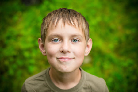 Close-up portrait of smiling little boy looking at the camera outdoorsの写真素材