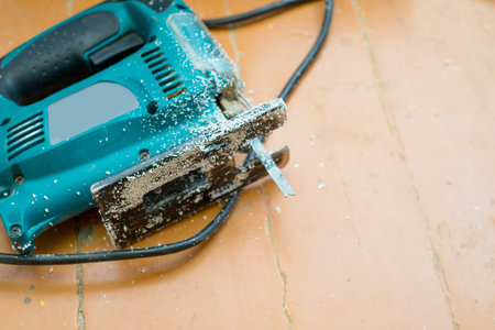 Close-up of jigsaw with sawdust on the floor indoors